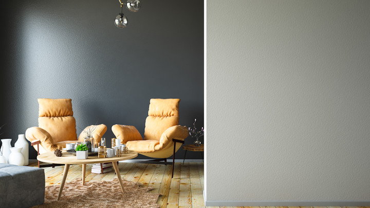 Salon avec mur gris foncé et deux fauteuils design.