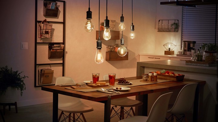 Sechs Lampen leuchten über einem gedeckten Esstisch in der Küche