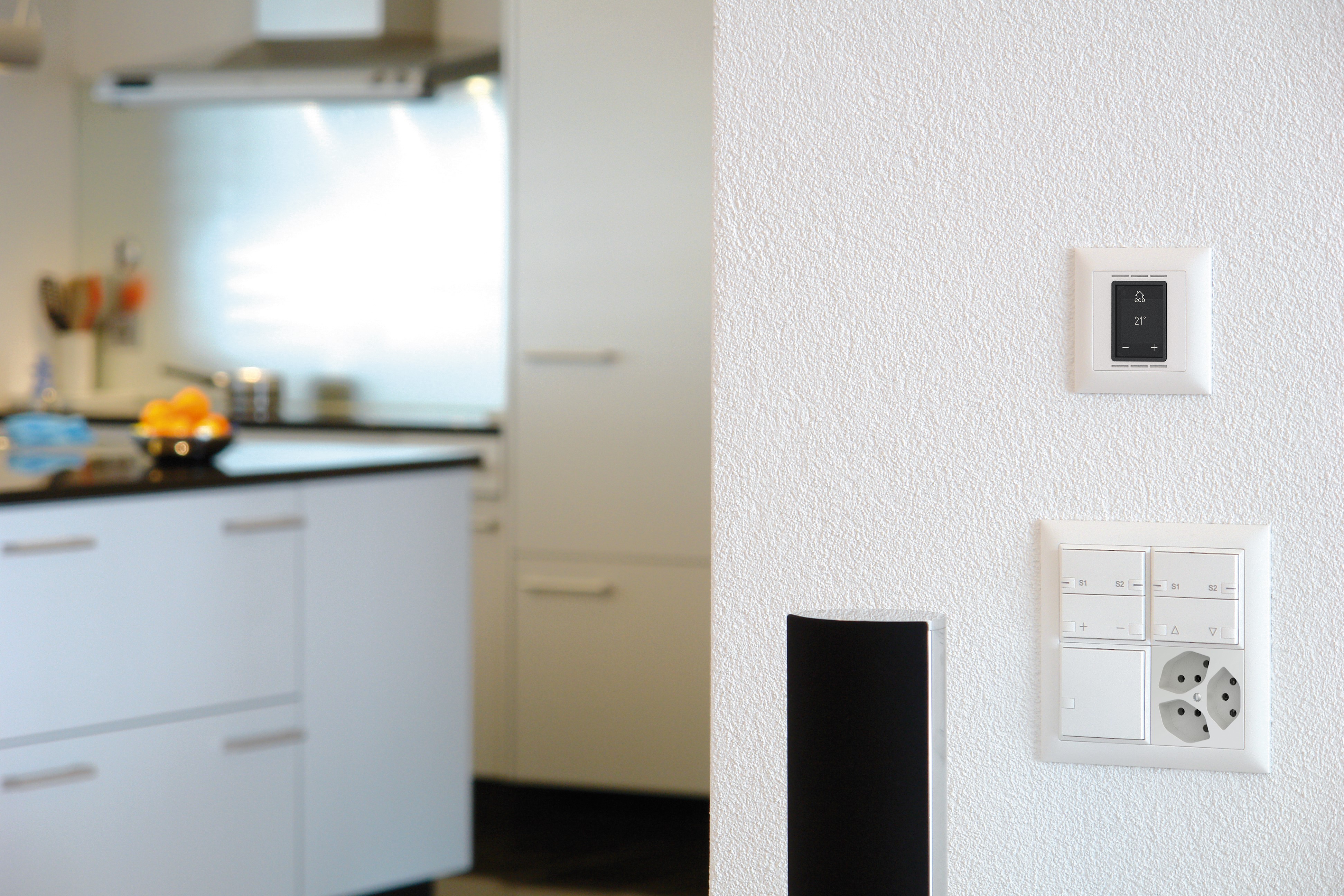 Thermostat d'ambiance en blanc installé sur un mur de cuisine blanc