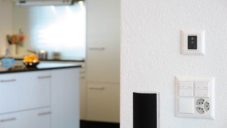 Thermostat d'ambiance en blanc installé sur un mur de cuisine blanc