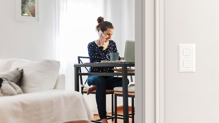 Une femme au téléphone est assise à son bureau dans un appartement