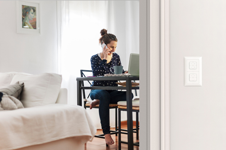 Una donna al telefono seduta alla sua scrivania in un appartamento